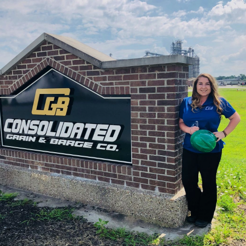 Josey Moore standing by Consolidated Grain & Barge Co. sign for her internshi